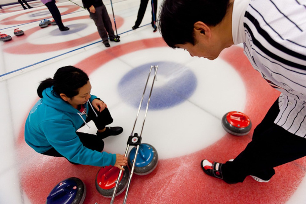Measuring her stone, Kris Ikegami of Team Schreiber confirms red is shot rock while Thomas Brandt of Team Gale-Seixeiro observes at the Granite Curling Club in Seattle on Monday, Jan. 9, 2012 during round one of Monday League playoffs. Founded in 1961 the Granite Curling Club is home to more national champions than any other curling club in the United States. (Photo/Neil Enns)