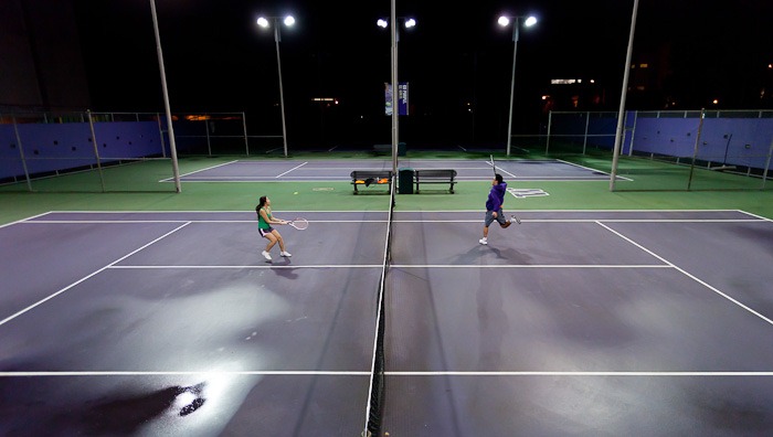 Crashing the net, Vicky Tran, left, and Kevin Huynh, right, play tennis under the lights at the University of Washington in Seattle, WA, on Thursday, Jan. 26, 2012. The cousins say they were craving tennis after growing up playing the game daily in their hometown of Kent, WA. (Photo/Neil Enns).